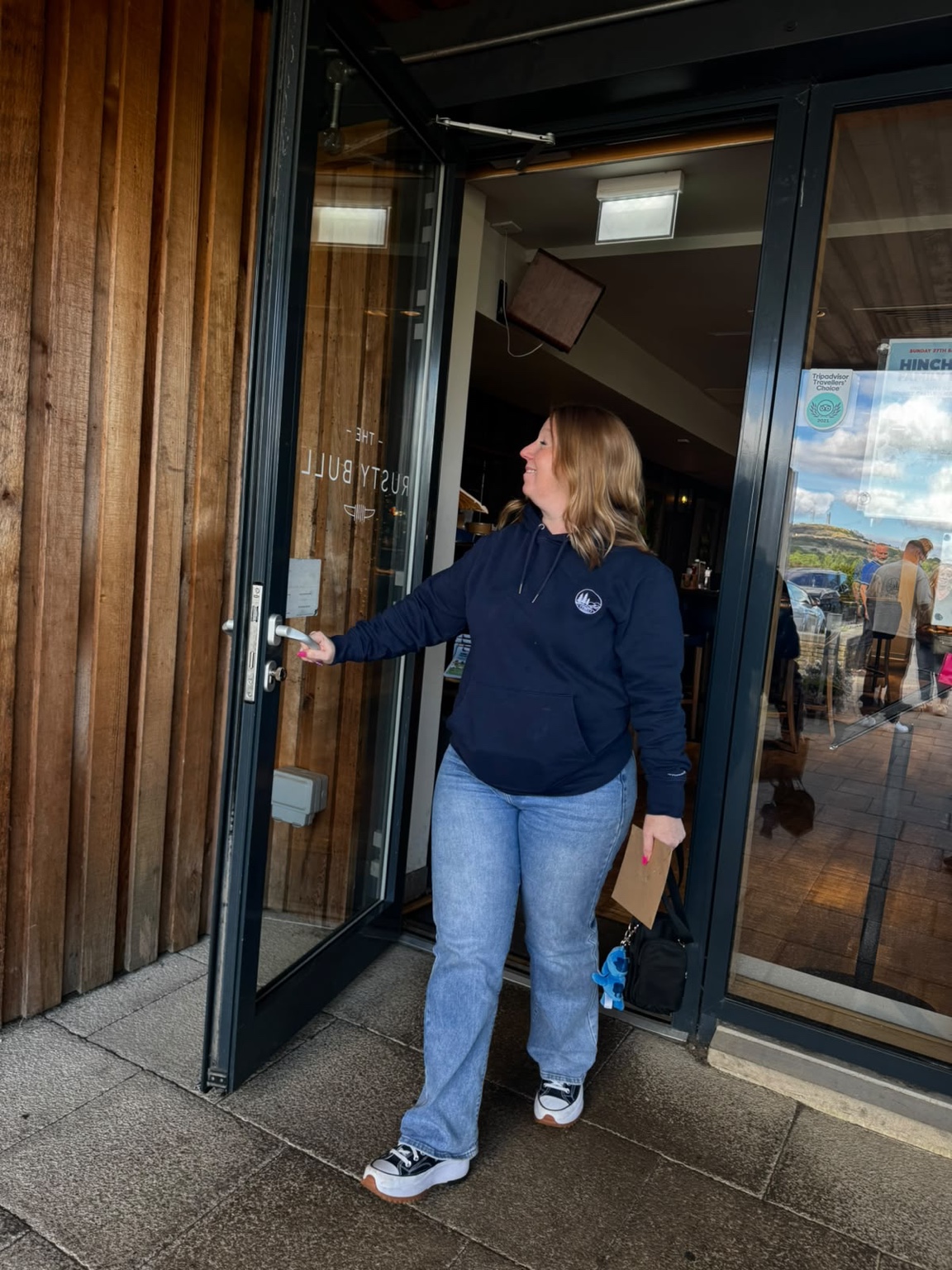 Bex leaving a cafe in a navy RippleNorth Northbound Hoodie