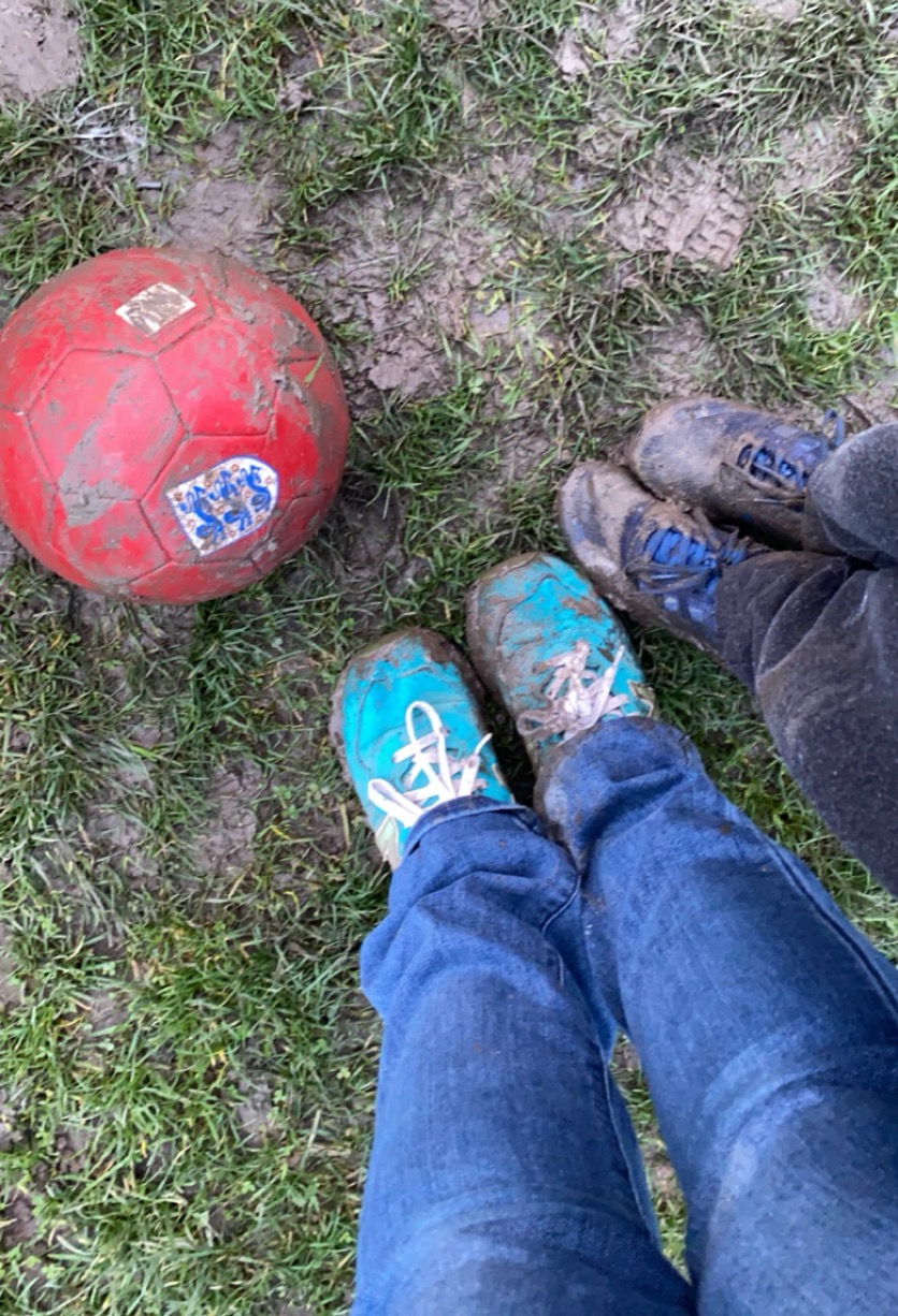 Muddy shoes beside a football after playing outside